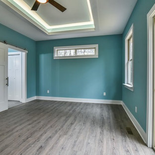 Modelo de dormitorio principal, de estilo americano, de tamaño medio, sin chimenea, con paredes azules, suelo vinílico y suelo marrón