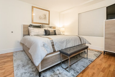 Mittelgroßes Modernes Hauptschlafzimmer ohne Kamin mit weißer Wandfarbe, braunem Holzboden und braunem Boden in Austin