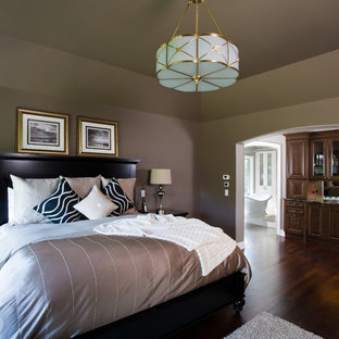 Modelo de dormitorio principal, tradicional, grande, con paredes marrones y suelo de madera oscura