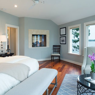 Mittelgroßes Modernes Hauptschlafzimmer mit blauer Wandfarbe, braunem Holzboden, Tunnelkamin und Kaminumrandung aus Stein in Washington, D.C.