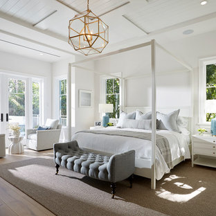 Example of a beach style master medium tone wood floor and brown floor bedroom design in Miami with white walls