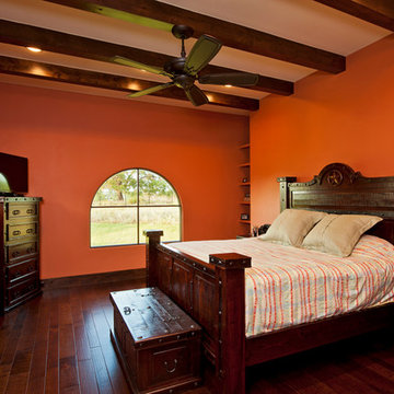 Master bedroom orange colored walls exposed beams hardwood floors
