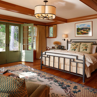 This is an example of a traditional master bedroom in Portland Maine with beige walls and medium hardwood flooring.