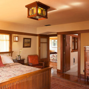 Diseño de dormitorio principal, de estilo americano, grande, con paredes amarillas y suelo de madera en tonos medios
