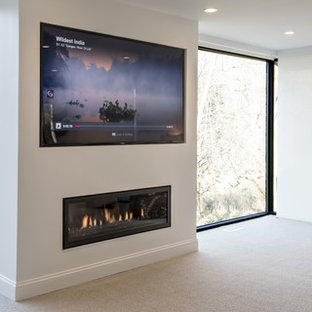 Imagen de dormitorio principal, moderno, grande, con paredes blancas, moqueta, chimenea lineal y marco de chimenea de yeso