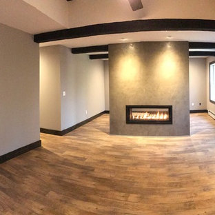 Ejemplo de dormitorio principal, rústico, grande, con chimenea de doble cara, paredes grises, suelo de madera en tonos medios y suelo marrón