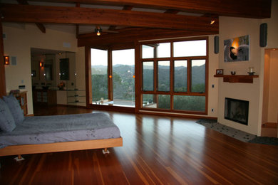 Ejemplo de dormitorio principal contemporáneo grande con paredes beige, suelo de madera en tonos medios, todas las chimeneas y marco de chimenea de yeso