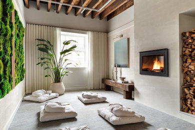 Example of a mid-sized trendy guest carpeted and blue floor bedroom design in New York with white walls, a hanging fireplace and a plaster fireplace