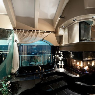 Imagen de dormitorio principal, mediterráneo, grande, con paredes beige, suelo de mármol, chimenea de doble cara, marco de chimenea de piedra y suelo negro