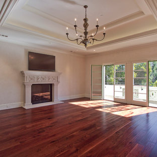 Foto de dormitorio principal, mediterráneo, extra grande, con paredes amarillas, suelo de madera oscura, chimenea tradicional y marco de chimenea de piedra