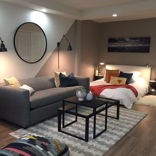 Modelo de dormitorio tipo loft, minimalista, de tamaño medio, sin chimenea, con paredes multicolor y suelo de madera clara