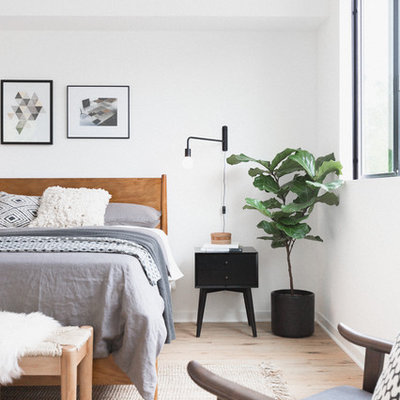 Example of a trendy master light wood floor and beige floor bedroom design in Los Angeles with white walls