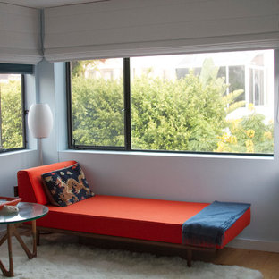 Ejemplo de dormitorio principal, retro, de tamaño medio, con paredes azules, suelo de madera en tonos medios, chimenea de esquina y suelo blanco