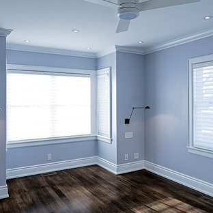 Modelo de dormitorio principal, clásico, pequeño, con paredes azules, suelo de madera en tonos medios, chimenea de doble cara y marco de chimenea de yeso