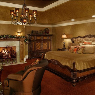 Diseño de dormitorio principal, mediterráneo, de tamaño medio, con paredes beige, moqueta, chimenea tradicional, marco de chimenea de piedra y suelo naranja