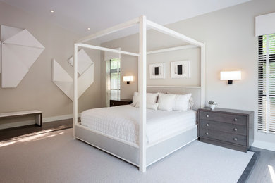 Modelo de dormitorio principal moderno grande sin chimenea con paredes grises, suelo de madera en tonos medios y suelo gris