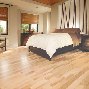 Modelo de dormitorio principal, rústico, con paredes beige y suelo de madera clara