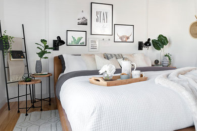 Modelo de habitación de invitados de estilo de casa de campo de tamaño medio con paredes blancas y suelo de madera clara
