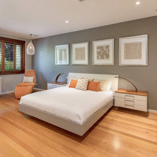 Contemporary bedroom in Canberra - Queanbeyan with grey walls, medium hardwood floors and brown floor.