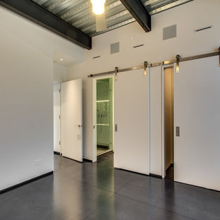 Diseño de habitación de invitados urbana con paredes blancas, suelo de cemento y suelo negro