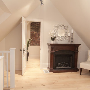 Foto de dormitorio tipo loft, minimalista, grande, con paredes grises, suelo de madera clara, chimenea tradicional y marco de chimenea de madera