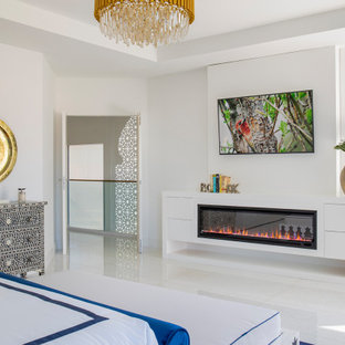 Imagen de dormitorio principal, minimalista, grande, con paredes blancas, suelo de mármol, chimeneas suspendidas, marco de chimenea de madera y suelo blanco