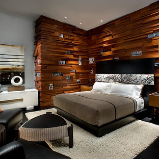 Ejemplo de dormitorio principal, minimalista, grande, con paredes marrones, suelo de madera pintada, chimenea de doble cara, marco de chimenea de piedra y suelo negro