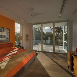 Modelo de dormitorio tipo loft, minimalista, grande, con parades naranjas, suelo de madera clara y suelo marrón