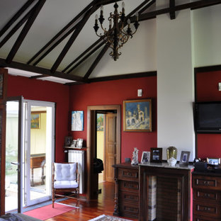 Immagine di una grande camera matrimoniale con pareti rosse, parquet scuro, stufa a legna, cornice del camino in legno e pavimento marrone