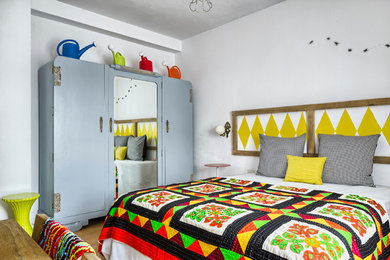 Mittelgroßes Stilmix Hauptschlafzimmer ohne Kamin mit weißer Wandfarbe und braunem Holzboden in Sonstige