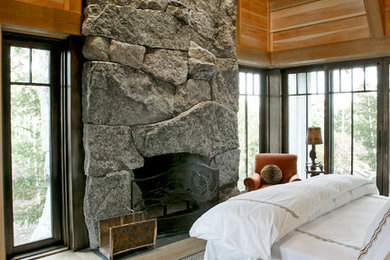 Large mountain style master light wood floor bedroom photo in Other with multicolored walls, a standard fireplace and a stone fireplace
