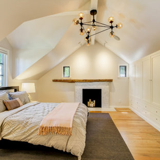 Modelo de dormitorio principal, clásico renovado, de tamaño medio, con paredes beige, suelo de madera en tonos medios, chimenea tradicional, marco de chimenea de baldosas y/o azulejos y suelo marrón