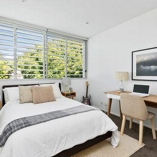 Design ideas for a beach style guest bedroom in Sydney with white walls, carpet and brown floor.