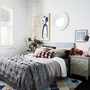Photo of a contemporary master bedroom in Melbourne with white walls, a standard fireplace and black floor.