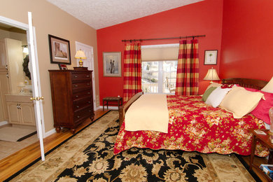 Example of a mid-sized classic master medium tone wood floor bedroom design in Other with red walls