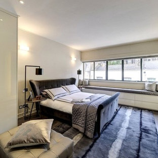 Large contemporary master bedroom in London with grey walls, dark hardwood flooring and brown floors.