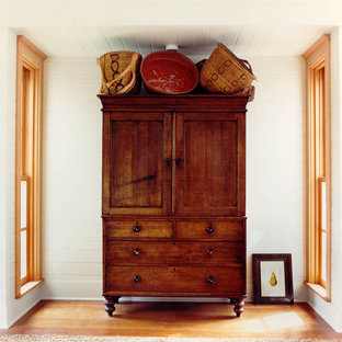 Diseño de dormitorio de estilo americano con paredes blancas y suelo de madera en tonos medios