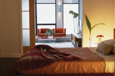Modelo de dormitorio principal moderno de tamaño medio sin chimenea con paredes beige y suelo de madera oscura