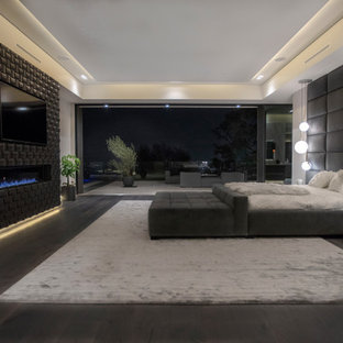 Ejemplo de dormitorio principal, minimalista, grande, con paredes blancas, suelo de madera oscura, chimenea lineal, marco de chimenea de baldosas y/o azulejos y suelo marrón