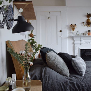 Modelo de dormitorio principal, escandinavo, grande, con paredes blancas, suelo de madera pintada, chimenea de doble cara, marco de chimenea de metal y suelo negro
