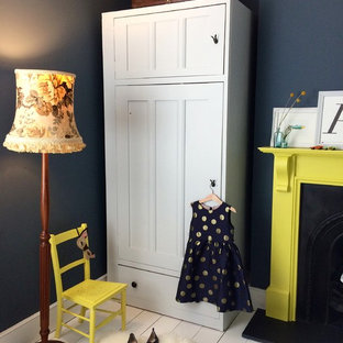 Modelo de dormitorio clásico renovado, de tamaño medio, con paredes azules, suelo de madera pintada, chimenea tradicional, marco de chimenea de madera y suelo blanco