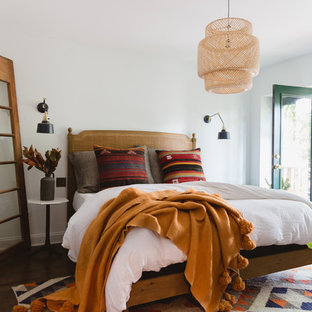 Foto di una camera da letto eclettica con pareti bianche, pavimento in legno massello medio e pavimento marrone