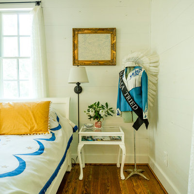 Example of a country medium tone wood floor and brown floor bedroom design in Austin with white walls