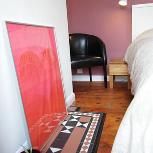 Imagen de dormitorio principal, bohemio, de tamaño medio, con paredes rosas, suelo de madera en tonos medios y marco de chimenea de baldosas y/o azulejos