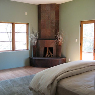 Modelo de dormitorio principal, clásico renovado, de tamaño medio, con paredes verdes, suelo de bambú, chimenea de esquina y marco de chimenea de baldosas y/o azulejos