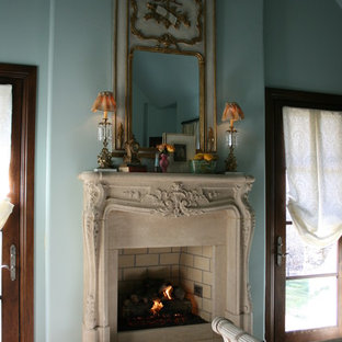 Diseño de habitación de invitados mediterránea, pequeña, con suelo de madera oscura, chimenea tradicional, marco de chimenea de piedra y paredes azules