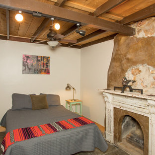 Imagen de habitación de invitados rústica, de tamaño medio, con paredes blancas, suelo de pizarra, chimenea tradicional, marco de chimenea de piedra y suelo multicolor
