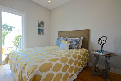 Imagen de habitación de invitados contemporánea pequeña sin chimenea con paredes grises y suelo de madera en tonos medios
