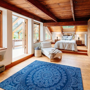 Ejemplo de dormitorio principal, exótico, con paredes blancas, suelo de madera en tonos medios y suelo marrón