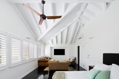 Diseño de dormitorio principal costero grande con paredes blancas, suelo de madera oscura y suelo negro
